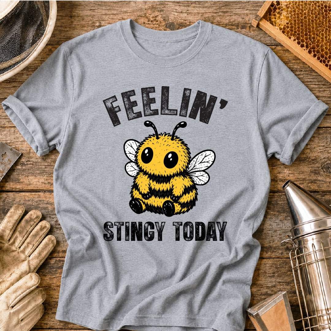 Cute bee shirt design featuring a fluffy cartoon honey bee with big eyes and the phrase “Feelin’ Stingy Today,” a funny bee pun graphic for beekeepers and bee lovers.