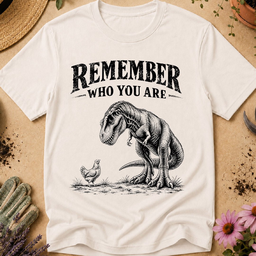 Funny chicken keeper shirt featuring a T. rex looking down at a chicken with “Remember Who You Are,” a humorous dinosaur chicken T-shirt for backyard chicken keepers and chicken lovers.