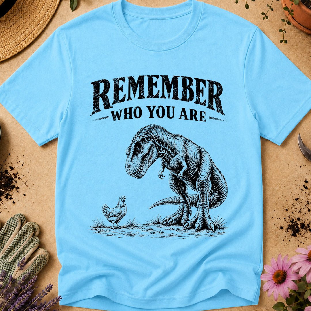Funny chicken keeper shirt featuring a T. rex looking down at a chicken with “Remember Who You Are,” a humorous dinosaur chicken T-shirt for backyard chicken keepers and chicken lovers.