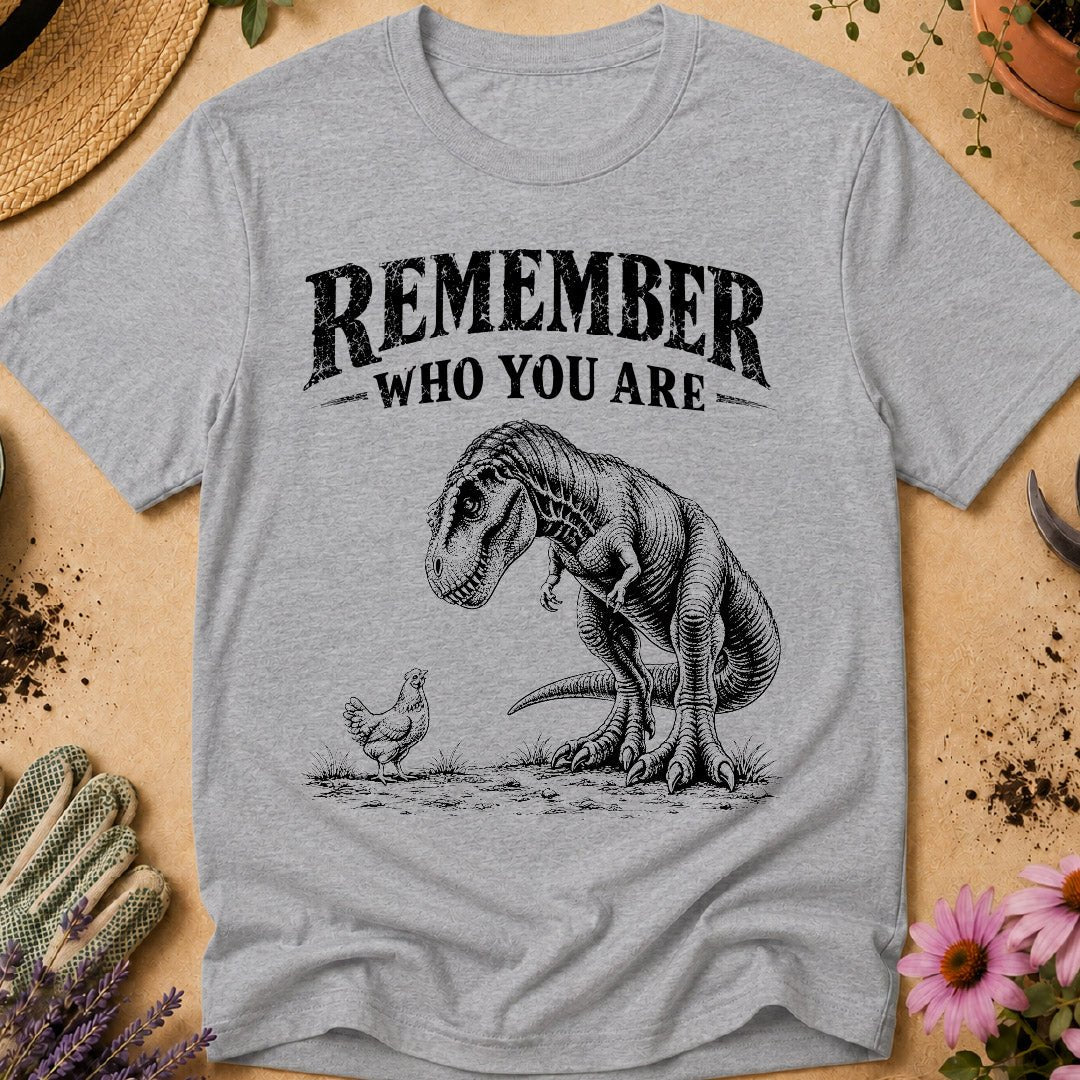 Funny chicken keeper shirt featuring a T. rex looking down at a chicken with “Remember Who You Are,” a humorous dinosaur chicken T-shirt for backyard chicken keepers and chicken lovers.